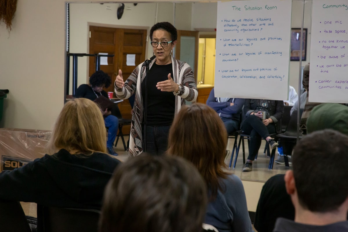 Frontline Arts Buffalo: A person is talking to a crowd with a whiteboard behind them