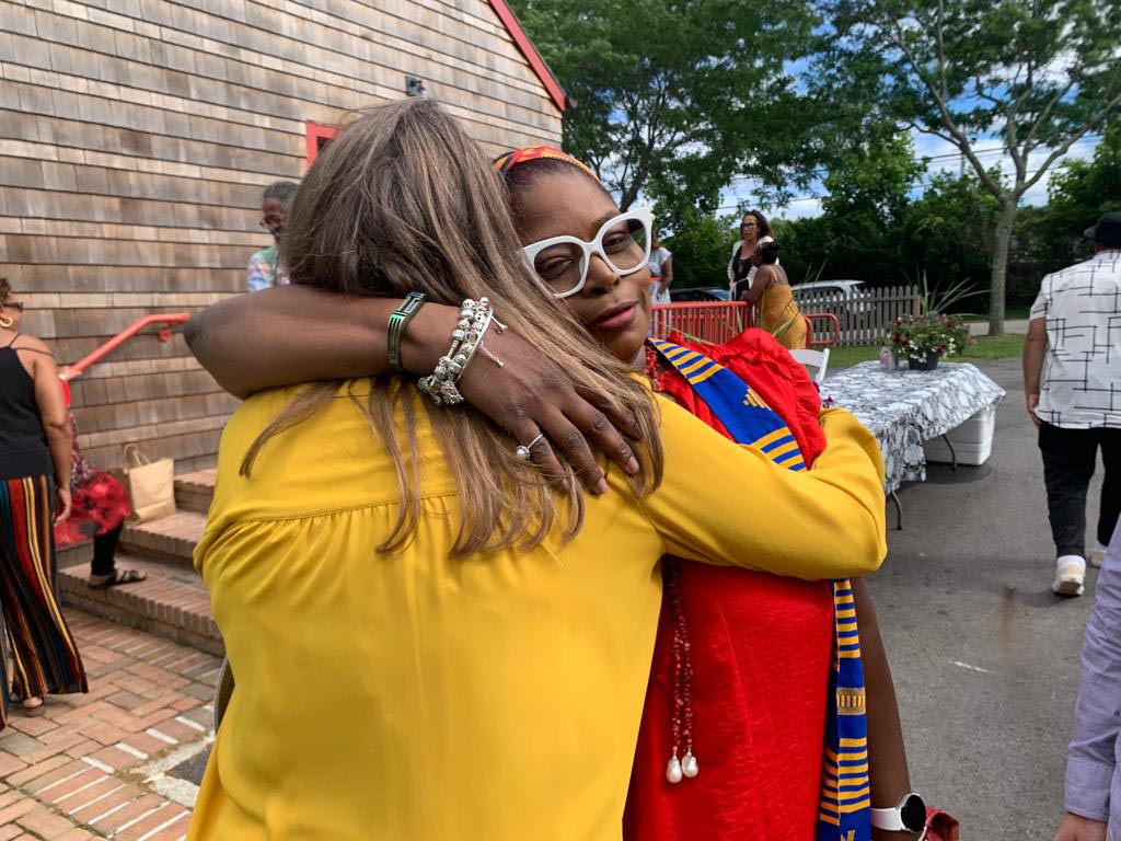 Southampton African American Museum: Two women hug each other - while we see the back of one woman's head, we see the face of the other - her face is relaxed and she looks comforted and at peace.