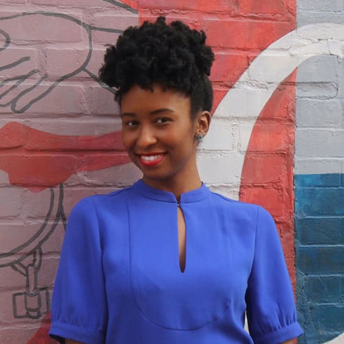 Stephanie Johnson-Cunningham, smiling at the camera in front of a painted mural.